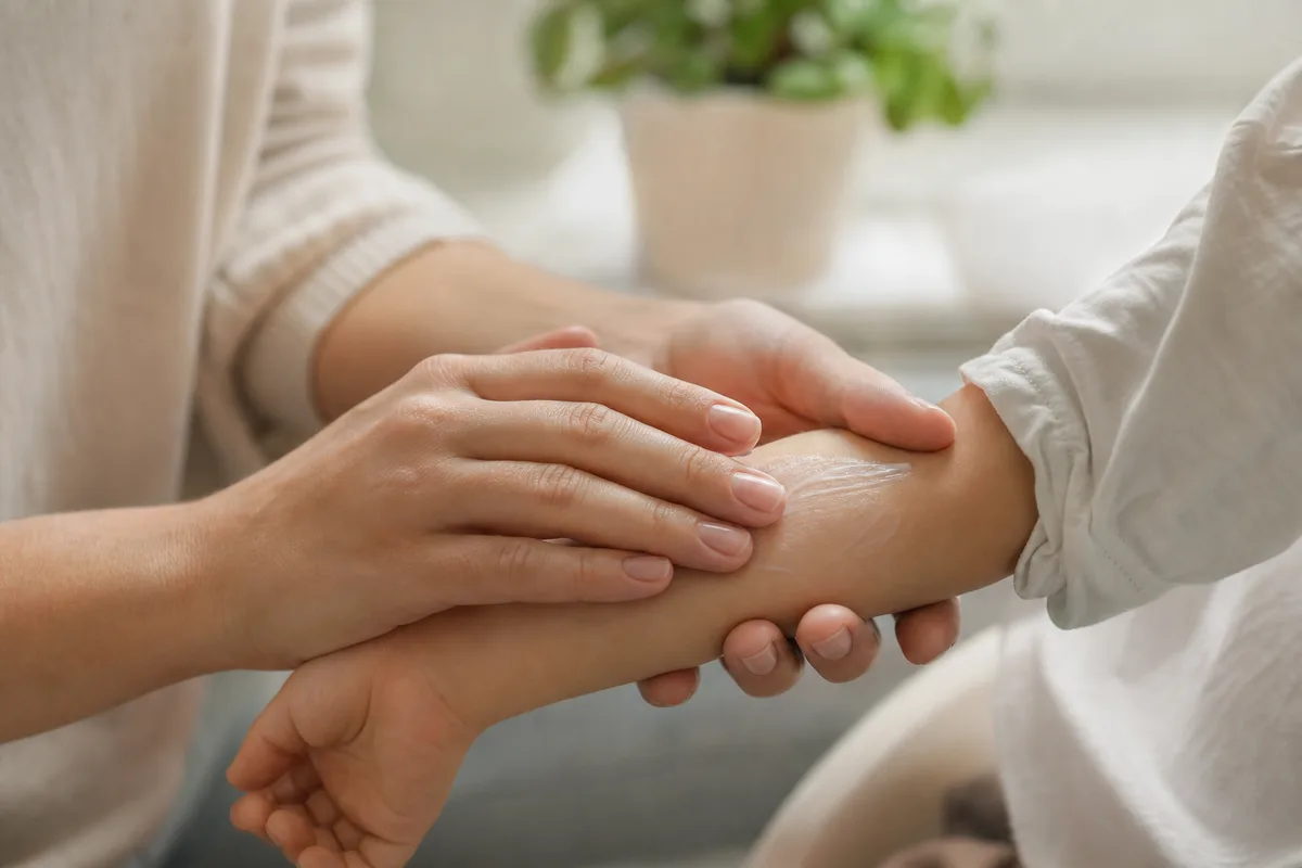 Application délicate d’un soin apaisant sur l’avant-bras d’un enfant, lumière naturelle